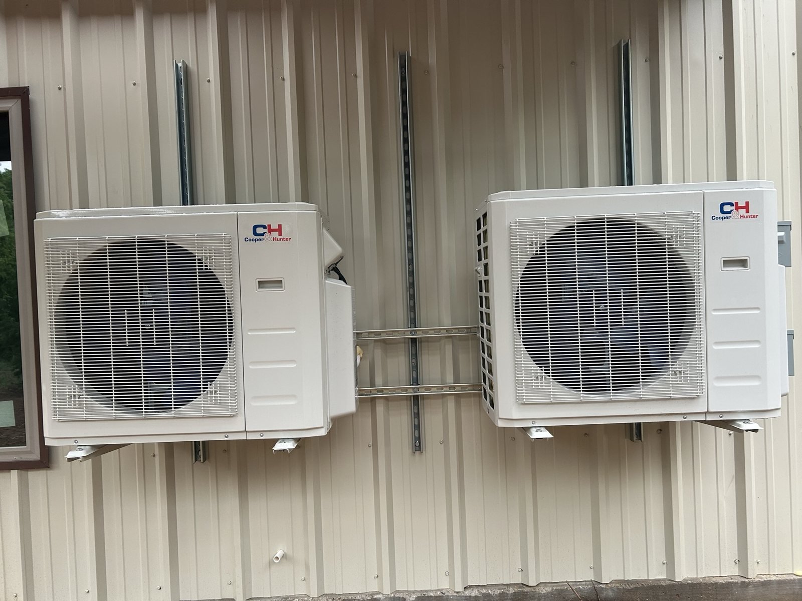 Exterior HVAC mini-split condenser equipment mounted on a metal building wall.