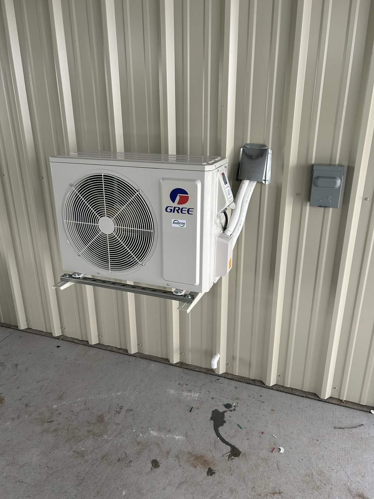 Exterior mini-split HVAC condenser with wall-mounted electrical disconnect.
