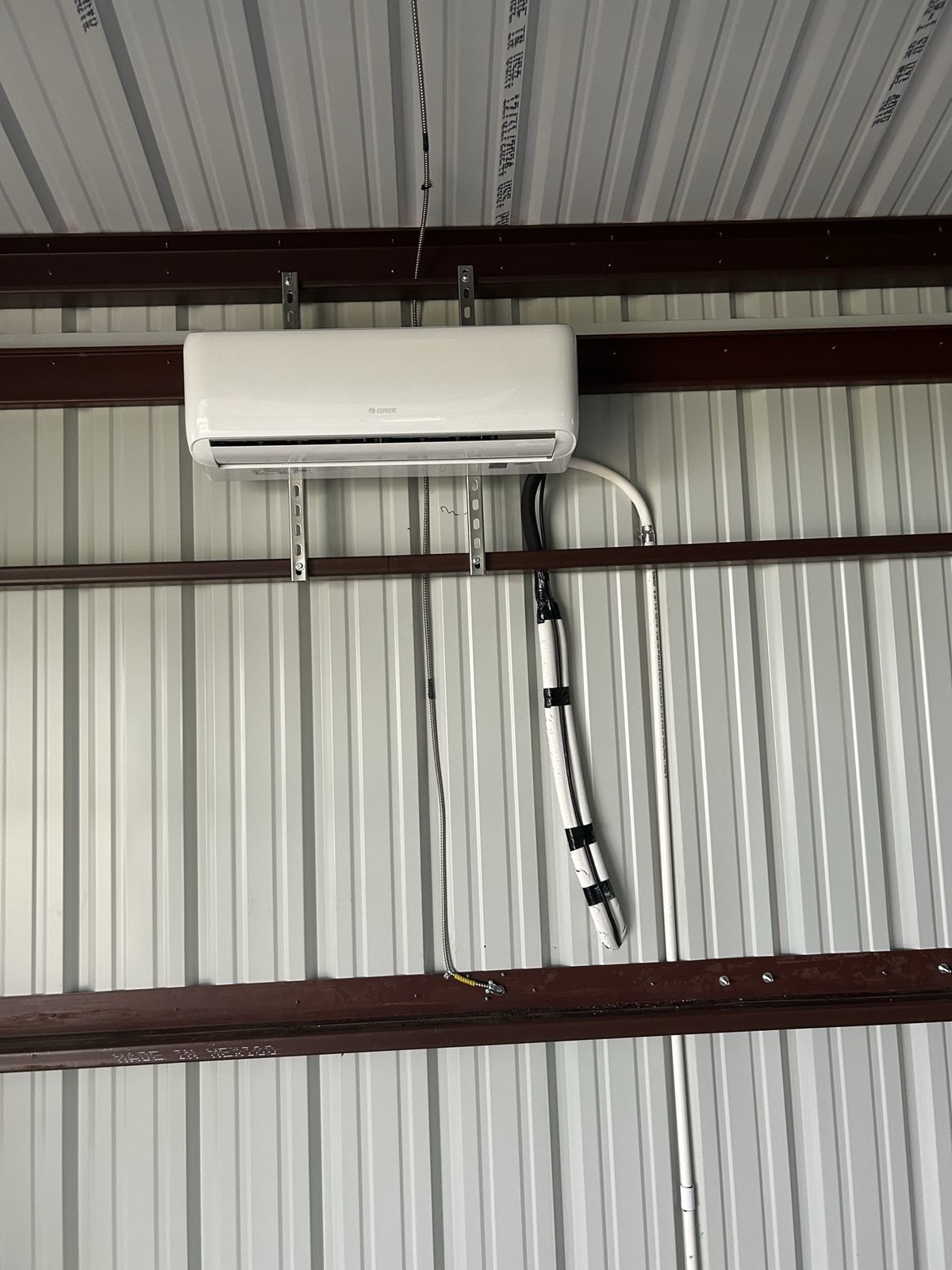 Interior HVAC mini-split head with clean conduit routing on a metal wall.