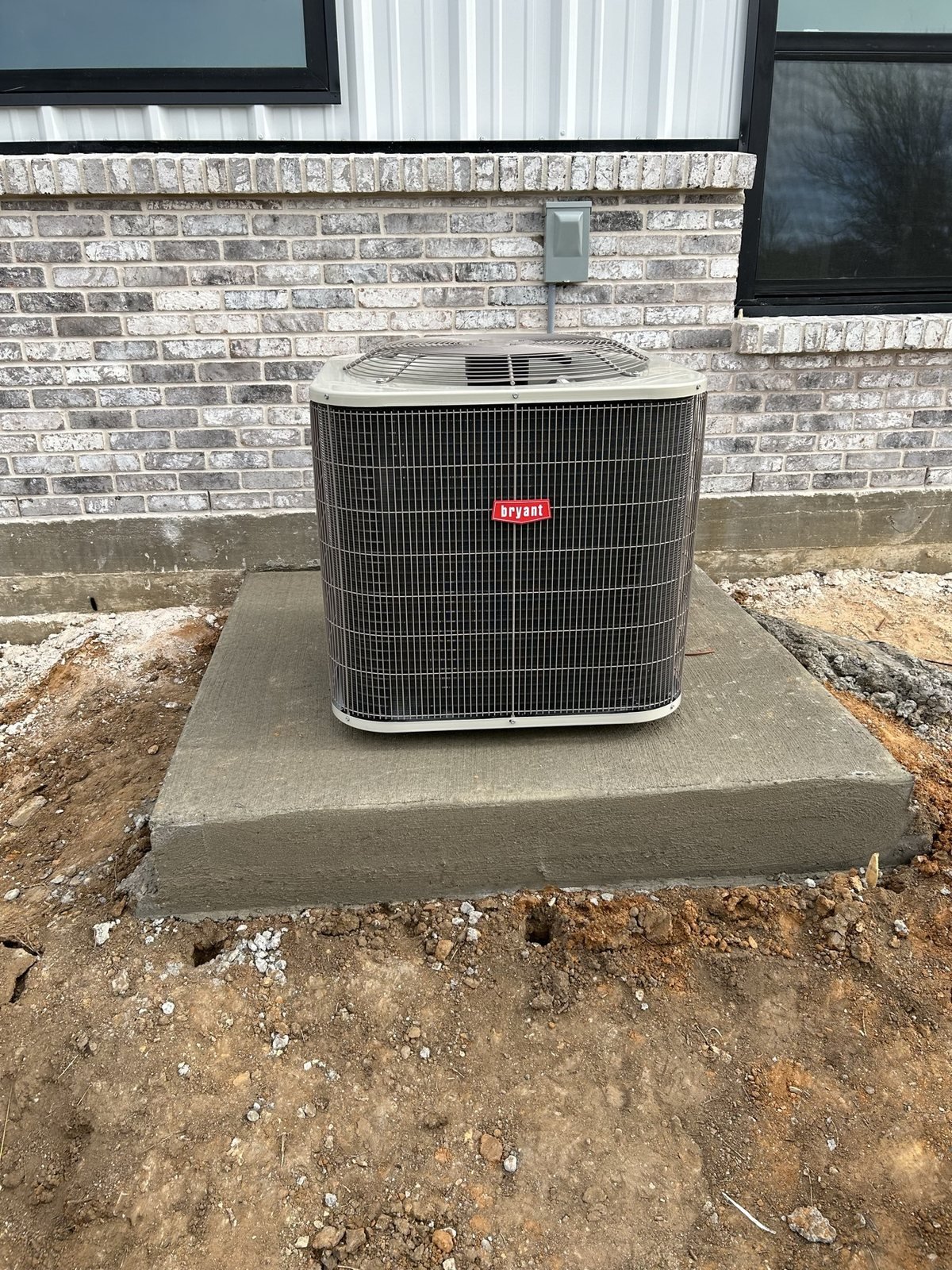 Outdoor HVAC condenser installed on a finished pad with line set routing.