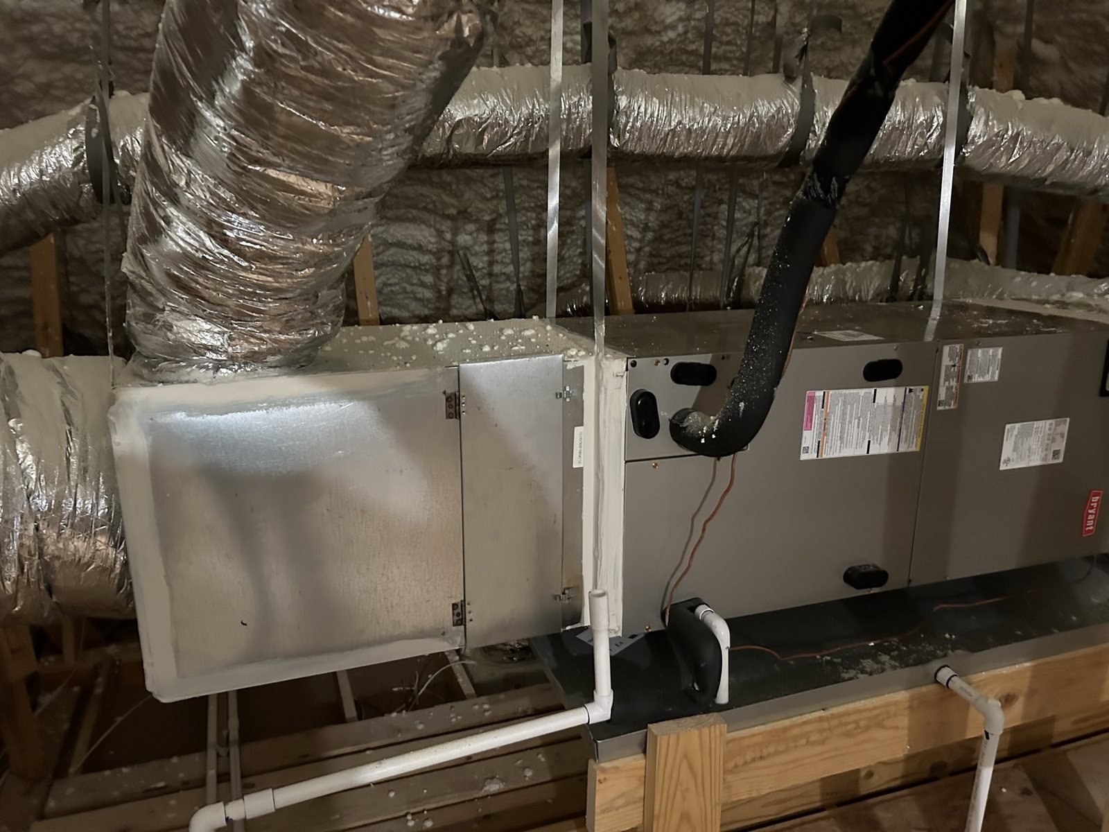 Attic HVAC air handler and duct equipment installed above a framed space.