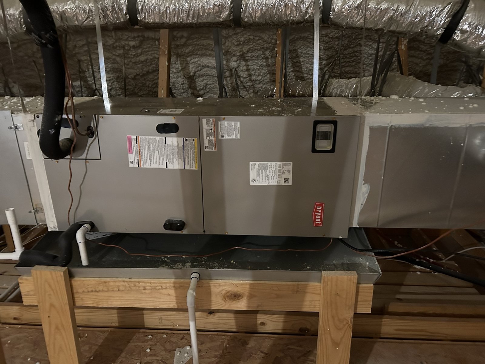 Attic HVAC air handler with duct and drain routing in new construction.