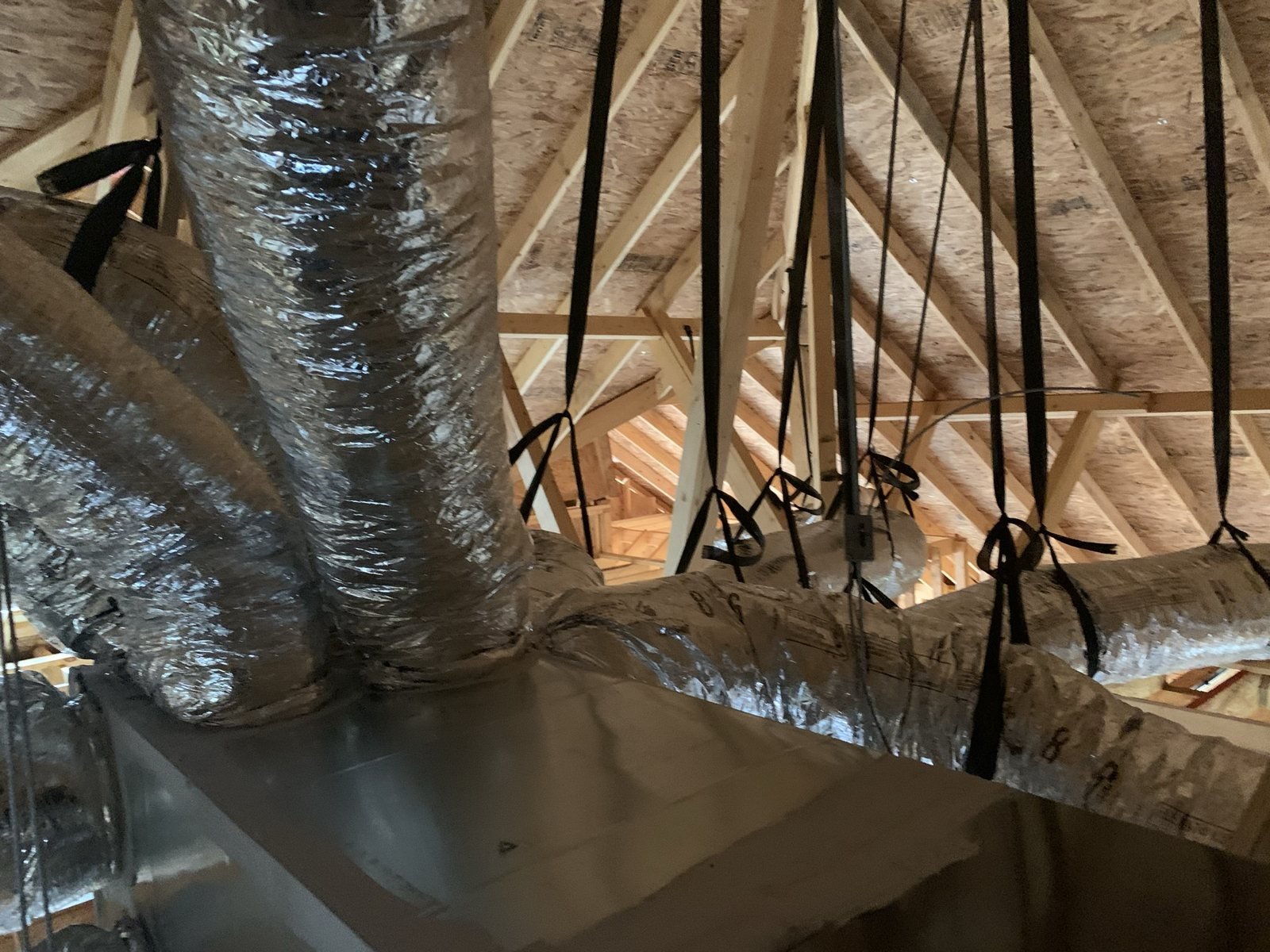 Attic ductwork and HVAC plenum installation in a wood-framed space.
