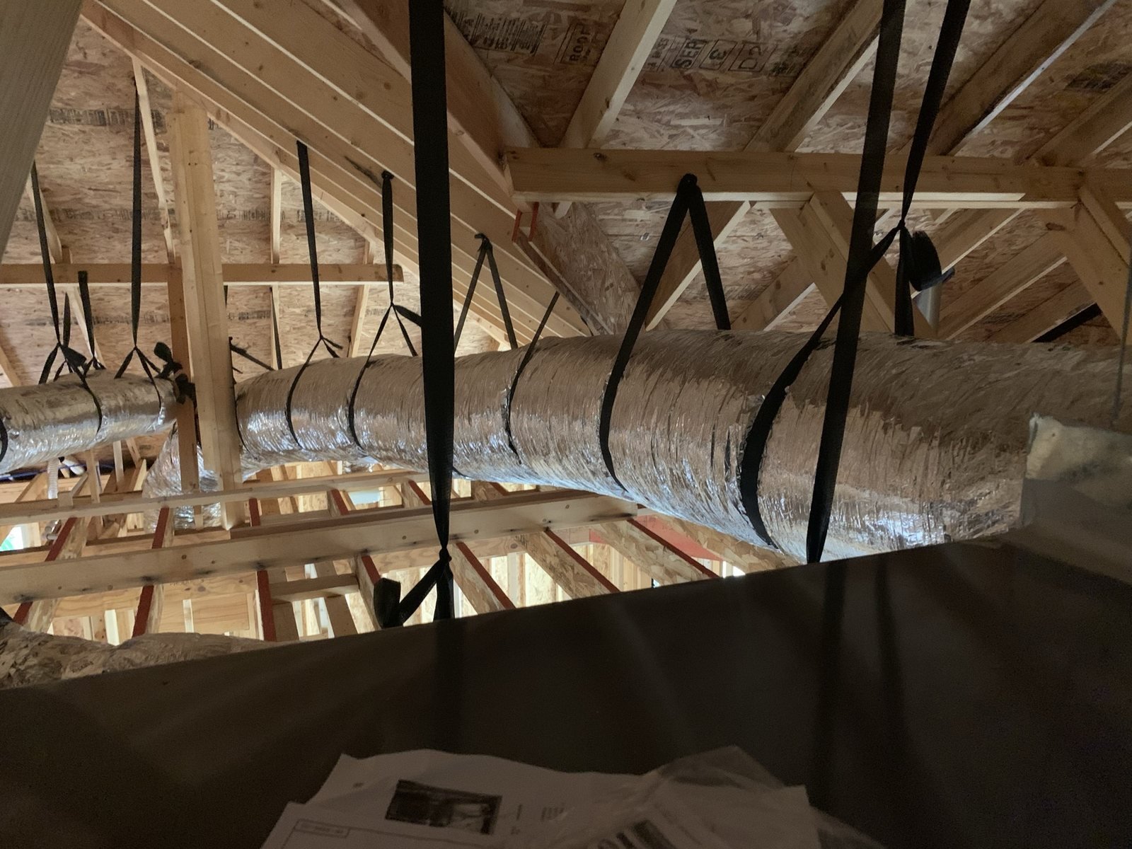 Flexible HVAC ductwork routed through a framed attic space.