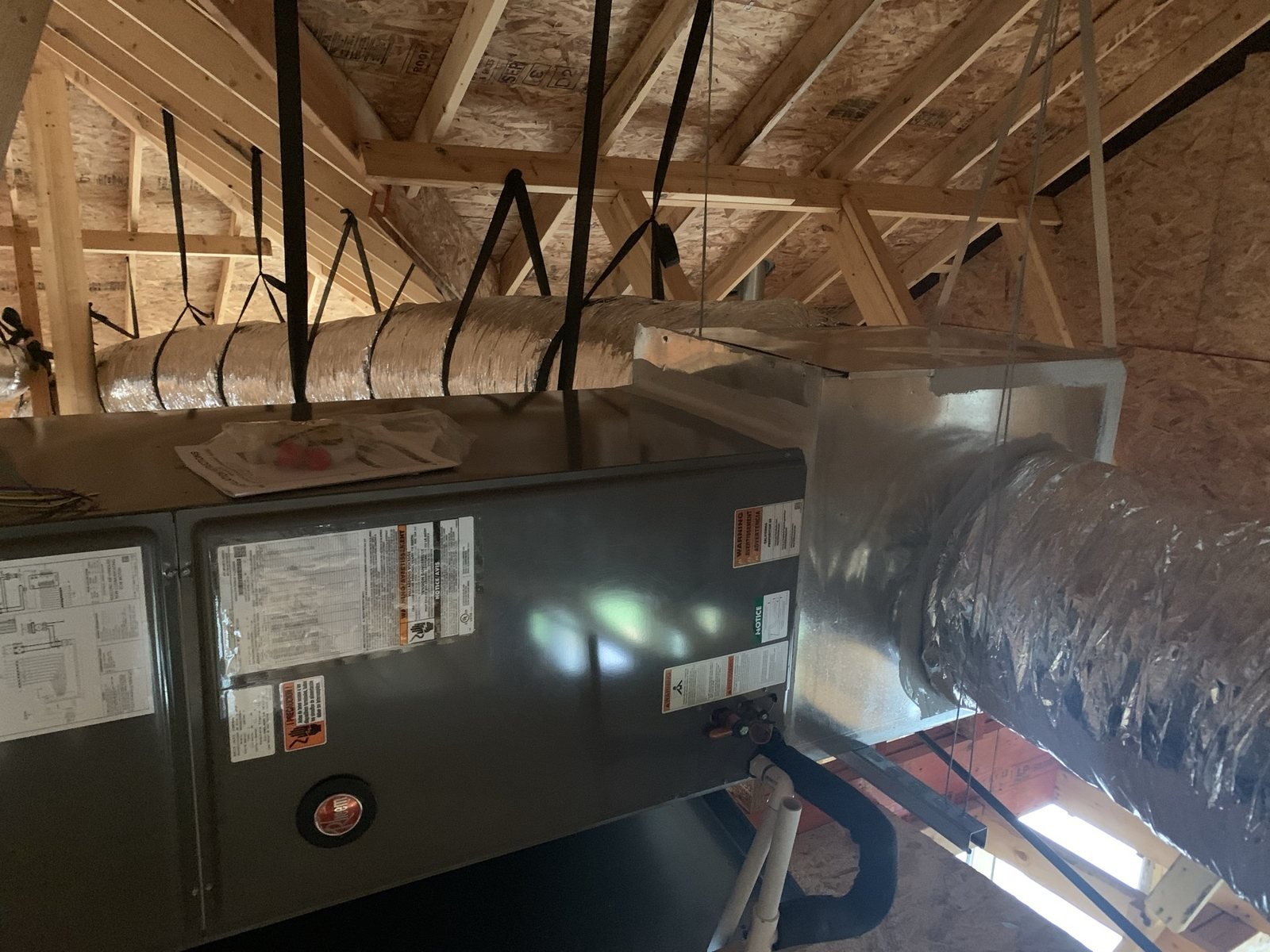 Attic HVAC equipment connected to ductwork in residential construction.